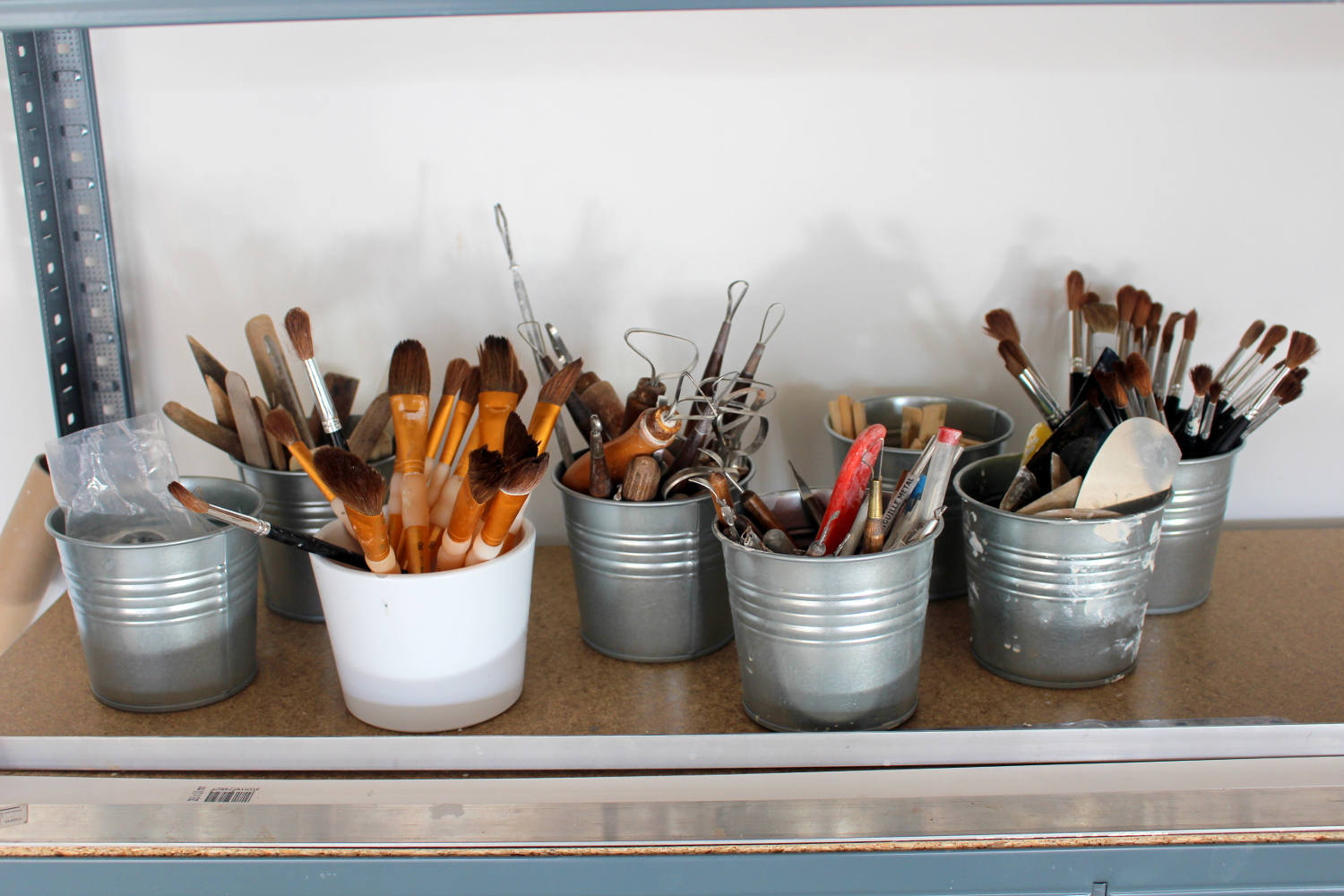 brushes organized in buckets on a shelf